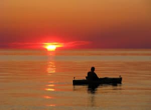 Kayaker on calm water at sunset